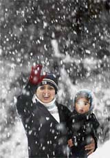A woman holds her son as they stand amid heavy snowfall at Patnitop, about 112 km north-east of Jammu, on Wednesday night. 