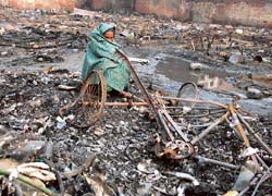 A jhuggi dweller sits on the remains of shanties that were reduced to ashes after a major fire in Ludhiana on Thursday.