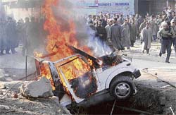 A protester throws stones at a burning jeep during a protest in Mugam, 30 km west of Srinagar, on Saturday.