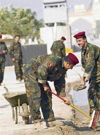 Iraqi soldiers clean up the road that leads to the Basra Palace on Saturday in preparation for a formal handover ceremony transferring security responsibilities for the Basra province from British forces to the central Iraqi government.