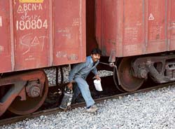 Unmindful of the danger it poses, a vendor crosses a railway track underneath a goods train at the railway station in Karnal. Such scenes are common here.