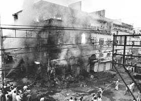 Bystanders look on as a building belonging to Sikh merchants burns in the Daryaganj District of New Delhi on November 2, 1984