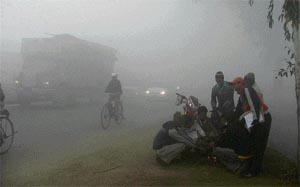 Passersby light a bonfire to escape from the cold on a foggy evening in Ludhiana on Wednesday.