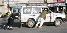 Traffic police personnel help the driver of a Tata Sumo, whose vehicle got stuck on a busy road in Jammu on Thursday.