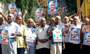 Malaysian ethnic Indian activists with shaven heads display portraits of Mahatma Gandhi in front of the Batu Caves temple in Kuala Lumpur on Thursday.