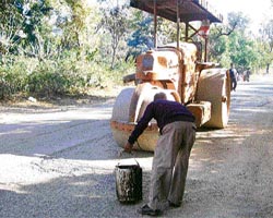 A labourer repairs the eroded bitumen surface of a 3-km stretch of the National Highway No. 20.