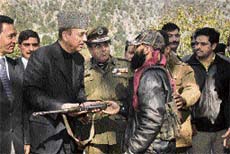 Manzoor Ahmad, divisional commander of the Hizbul Mujahideen, lays down arms before Chief Minister Ghulam Nabi Azad at Ramban on Sunday.