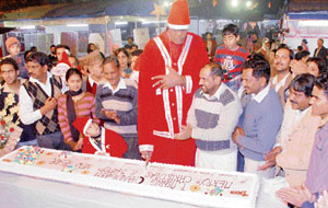 Eight-foot-tall, Ram Lal Shindia, cuts an eight-foot-long cake at a kids carnival in Sector 34, Chandigarh, on the eve of Christmas on Monday.