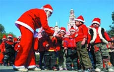 A girl in Santa Claus attire distributes goodies among kids on the eve of Christmas at the Gole Dakhana Church in the Capital on Monday. 