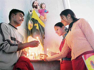 Youngsters light candles on the Christmas eve at Catholic Church in Ambala on Monday.