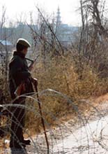 Policemen stand guard outside the mosque where militants hold two civilians hostage in Palnoo village of Kulgam.