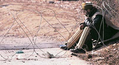 Policemen stand guard outside the mosque where militants hold two civilians hostage in Palnoo village of Kulgam.