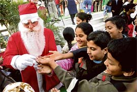 A person dressed as Santa Claus distributes sweets during Christmas celebrations in Jammu. 