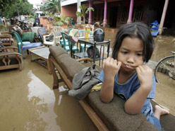 A child sits on a bench after mud hit her house in Madiun district, Indonesia's East Java province, on Thursday. Landslides and floods triggered by heavy rain have left over 120 persons dead or missing on Indonesia's Java island, as rescuers struggled to pull out bodies buried under thick mud, officials said.