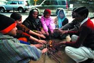 People warm themselves with firewood on a cold Sunday evening in the Capital.