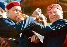 BJP vice-president Shanta Kumar offers sweets to Dhumal after the swearing-in ceremony.