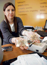 A Cypriot bank employee holds official sealed bags containing local euro coins at a bank in Nicosia on Monday.