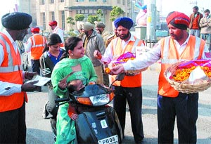 Traffic policemen present flowers to commuters during the traffic safety week at BMC Chowk in Jalandhar on Thursday.
