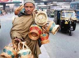 A Kashmiri vendor carries traditional firepots (Kangari) for sale at Hari Singh High Street Market in Srinagar on Friday.