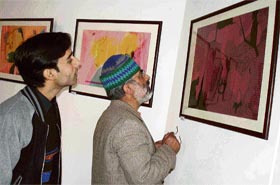 Visitors look at a painting during an exhibition at the Kala Kendra in Jammu
