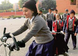 A girl cycles to school while some other students walk down braving the chill, in Chandigarh on Monday.