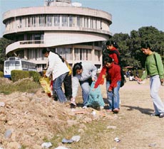 Students pick up litter strewn around the Panjab University campus in Chandigarh on Monday.