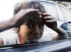 A beggar asks a city resident for arms while endangering her life on a busy traffic chowk in Ludhiana on Monday.