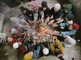 Schoolchildren warm their hands near a bonfire on a cold day in Jammu on Tuesday. 