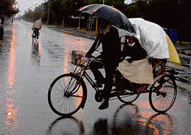 A rickshaw-puller carries schoolchildren during rain in Chandigarh on Wednesday.
