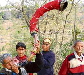 a person blows a local musical instrument at Jol Sappar, near Nadaun, as a mark of welcome