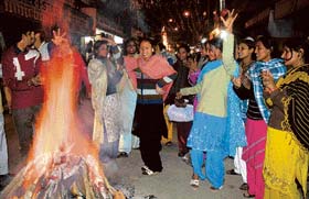 People dance around a bonfire on the occasion of Lohri in Jammu on Sunday.
