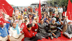 Members of the CPM protest at the local bus stand in Chandigarh on Monday