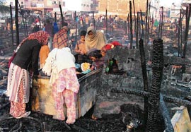 Women try to salvage belongings on Monday after the fire in the Chakarpur slum in Gurgaon on Sunday night. 