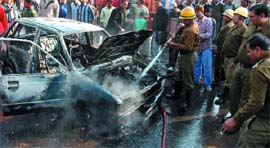 A fireman tries to douse the fire in Maruti 800 car at Mandi House in the Capital on Monday.