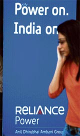 A girl talks into her mobile phone as she walks past a poster of Reliance Power on the last day of the IPO subscription in Mumbai on Friday.