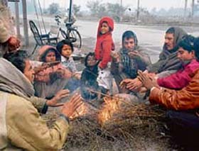 A group of people sit around the bonfire to get warmth as mercury dips in the region.