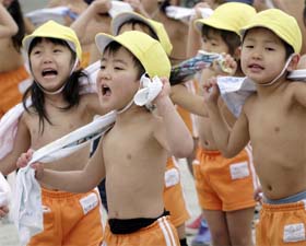 Kindergarten children, naked to the waist, rub themselves with dry towels after a workout in a playground at Tokyo's Mizuho kindergarten