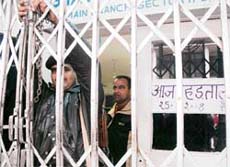 SHUT OUT: A security guard puts the lock on the gate of the SBI branch in Sector 17, Chandigarh, on Friday.