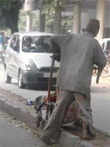 a beggar along with a child on a trolley crosses the road in a risky manner on seeing a car coming from the opposite direction