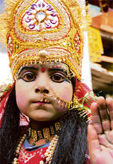 A small girl dressed as Hindu goddess asking for alms outside a Hindu temple in Jammu. 