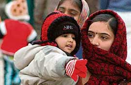 A mother and her child keep warm from chilling cold by wrapping themselves in woolens at Sukhna Lake, Chandigarh.