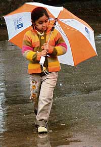 A girl walks in the rain with an umbrella.