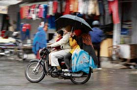 Unmindful of the risk involved, a family rides a motorcycle during rain in Karnal