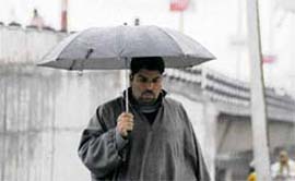 Rain rain chill again: A man wearing a Kashmiri phiran and carrying an umbrella shields himself from the rain in Jammu on Sunday.