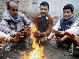 Labourers warm up around a bonfire at a road side in Amritsar on Sunday.
