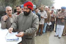 People wait in a queue to get the documents of their vehicles checked near the Sirhand canal bridge on Monday. 