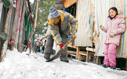 A shopkeeper removes snow from in front of his shop in the Tibetan market in Shimla