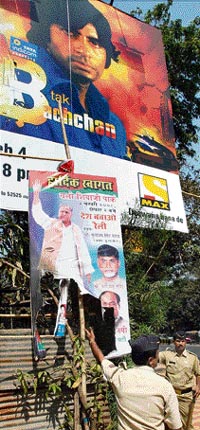 Police personnel show the burned poster of Samajwadi Party supremo Mulayam Singh Yadav in Mumbai on Monday.