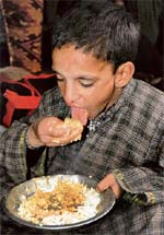 Not snow flakes, a child at Jammu bus stand eats rice to fill his stomach