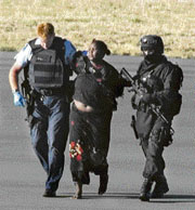 A woman (centre) is escorted by the New Zealand police across the tarmac at Christchurch airport on Friday.